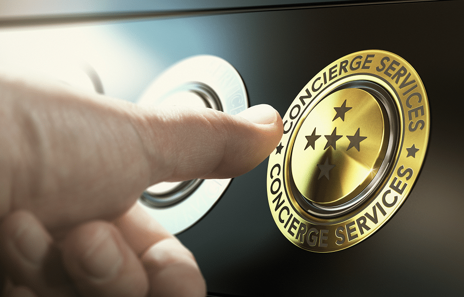 Doigt pressant un bouton doré gravé "CONCIERGE SERVICES" et orné de trois étoiles, évoquant un service de luxe et haut de gamme.